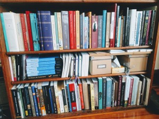 My bookshelf section. There are three shelves, and the middle shelf is too-small and a mess.