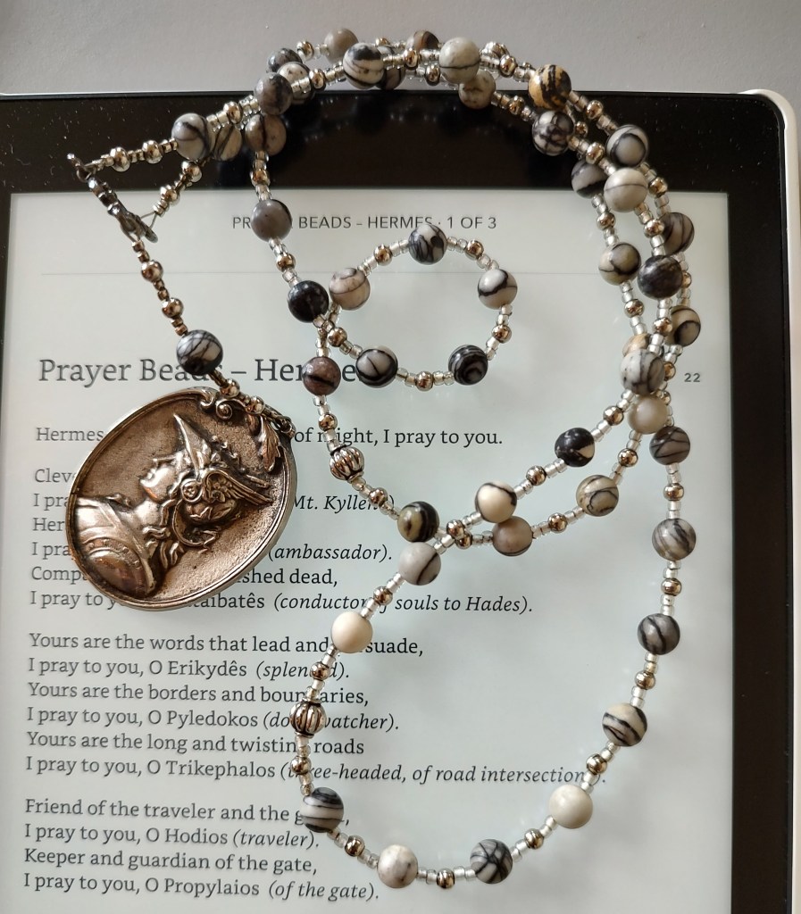Prayer beads for Hermes on top of an ereader.