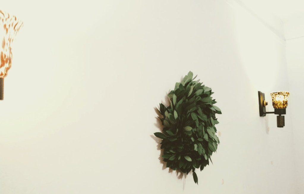 A bay laurel wreath on a wall. There are some lamps as well.